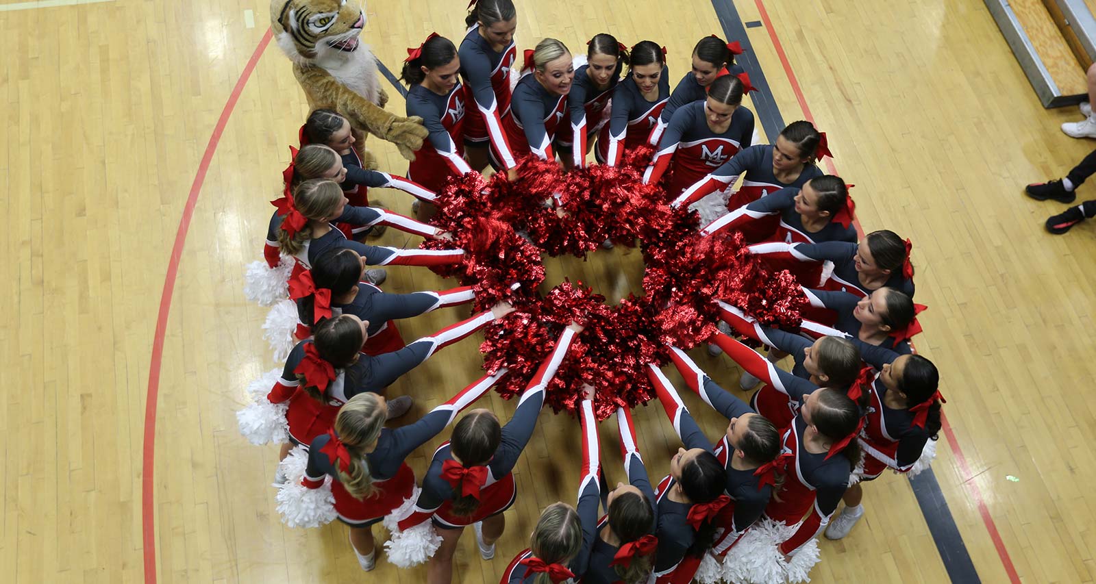 Cheer team circles with hands toward the center of the circle.